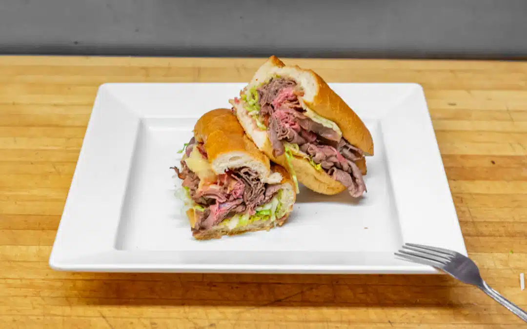 Two roasted beef sandwiches with cheddar and bacon