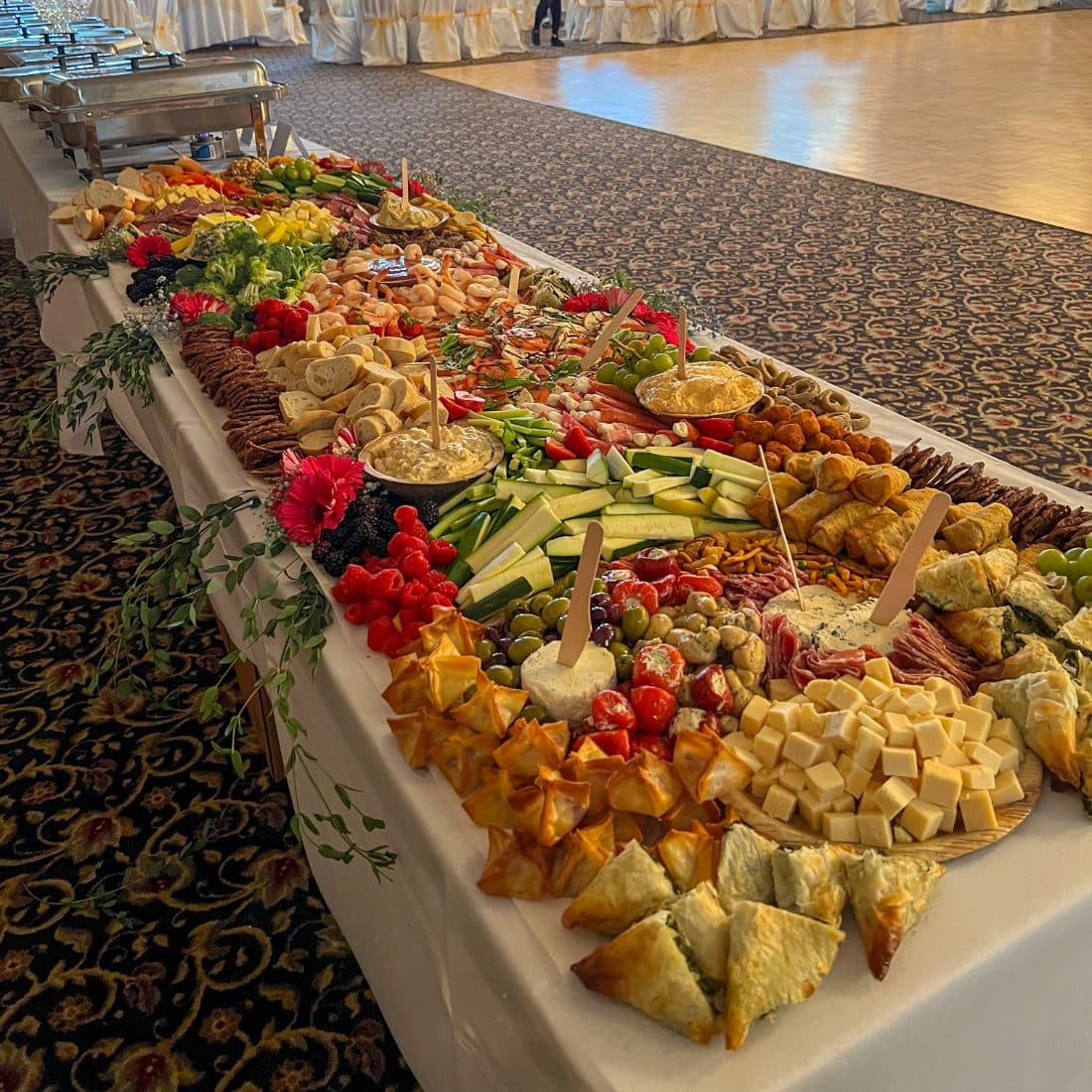 Long grazing table of Italian meats, cheeses, fruit and pastries set up at an event
